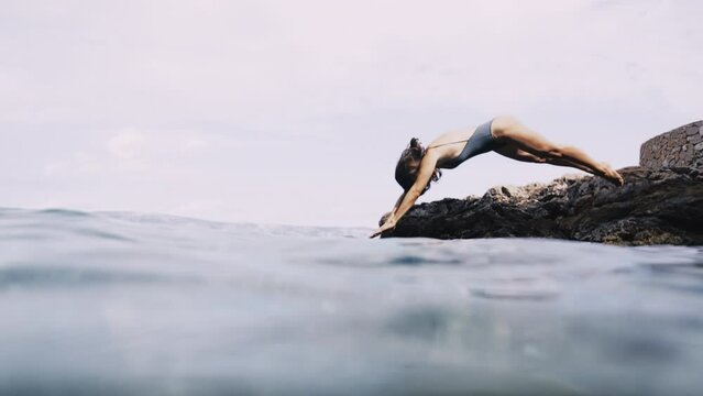 Slow motion shot of girl jumping into the sea following her underwater