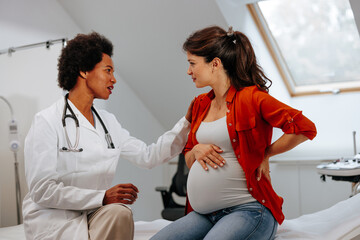 Doctor advising pregnant woman at hospital.