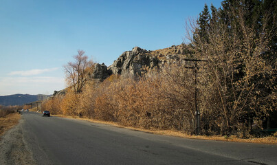 Asphalt road. Autumn landscape. Yellow trees and blue sky. Rocky mountains. Ust-Kamenogorsk (kazakhstan)