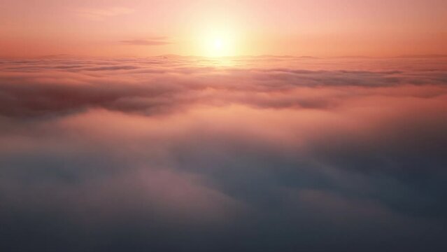 Camera is raising above the sea of endless clouds at golden sunset hour. Beautiful ASMR nature landscape and heavenly orange sun rays. 