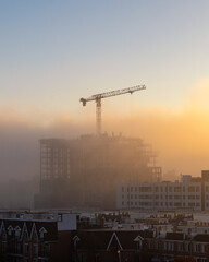 Fog blanket moving in at sunset over a construction site and crane. Toronto Ontario