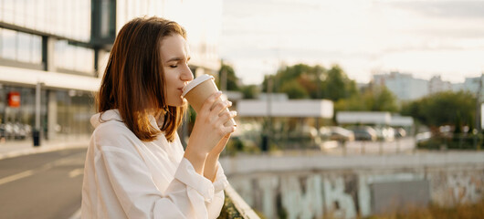 Image of young woman enjoying her morning coffee outdoor in city .