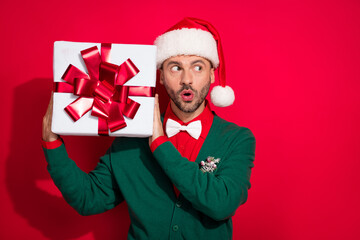 Photo of sweet impressed man wear x-mas bowtie green cardigan guess inside noel present empty space isolated red color background