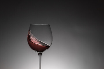 Moving red wine inside a glass. Back lighting, studio shot. Copy space.