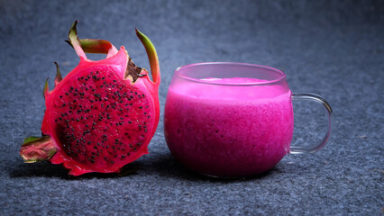 A glass of dragon fruit juice with a Slice of fresh dragon fruit on dark background. Healthy drink...