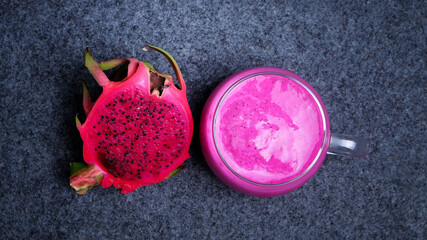Top view of a glass of dragon fruit juice with a Slice of fresh dragon fruit on dark background....