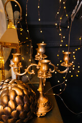 a gold-colored chandelier against a black wall, a New Year's garland and other gold-colored decorations
