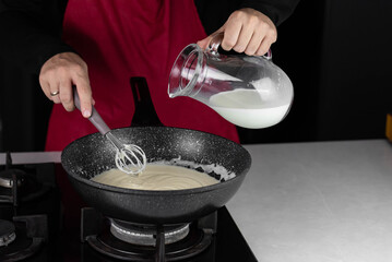 Chef cook making white cheese sauce for mac and cheese meal. Ingredients: Milk, cheese, flour and...