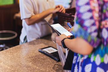 Woman customer scanning QR code payment via mobile phone at cashier counter in store.