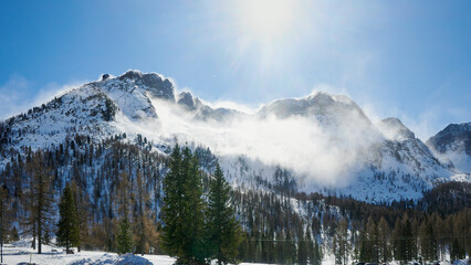 Zimowa panorama skalistych gór pokrytych śniegiem. Zdjęcie pod słońce.