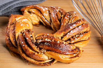 Roscón de reyes Kringle Estonia. Typical Christmas sweet, braided sponge cake with cinnamon, butter, walnuts or almonds and icing sugar on a white background.