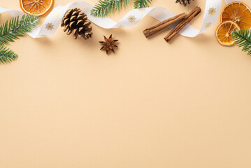 Christmas decorations concept. Top view photo of dried orange slices cinnamon sticks pine cone anise curly ribbon and fir branches on isolated beige background with copyspace