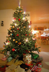 Christmas tree with lights, ornaments and presents in the family home in December