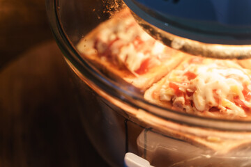 Baking homemade pizza with bread and cheese in dirty electric glass air fryer oven