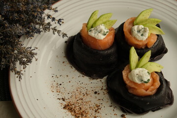 Festive bright appetizer. New Year's table. black pancakes with cuttlefish ink, salmon and avocado. black food. pancake week. Vegetarian pancakes. seafood. Useful lunch. homemade food