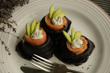 Festive bright appetizer. New Year's table. black pancakes with cuttlefish ink, salmon and avocado. black food. pancake week. Vegetarian pancakes. seafood. Useful lunch. homemade food