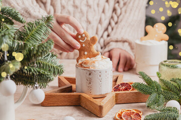 White cups of hot cocoa with whipped cream decorated with gingerbread man.