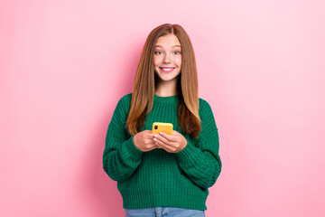 Photo of young positive toothy beaming smile girlish woman wear green knitted jumper hold smartphone popular blogger isolated on pink color background