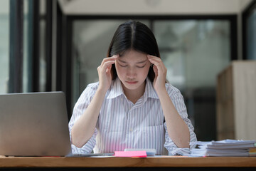 Stressed Asian business woman worry with many document on desk at office