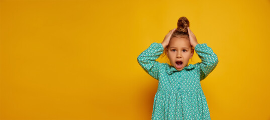Surprised child. Cute little girl, kid with long curly hair looking at camera isolated over yellow background. Concept of children positive emotions, beauty