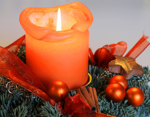 Christmas decoration with burning candle light stick and in orange colours 