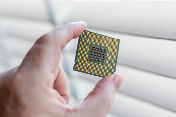 A hand holding a CPU showing the bottom side of the processor.
