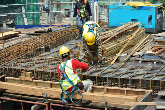 MALACCA, MALAYSIA -MARCH 30, 2016: Construction workers fabricating steel reinforcement bar at the construction site in Malacca, Malaysia. The reinforcement bar was ties together using tiny wire.  