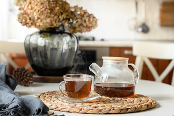 Cup of tea and glass teapot in modern kitchen. Still life in home interior. Close up. Tea time, cozy atmosphere.