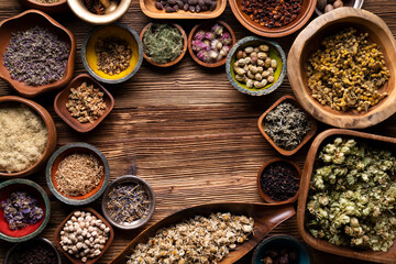 Natural medicine background. Assorted dry herbs in bowls, mortar and plants on rustic wooden table.