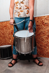 Unrecognizable girl playing a drum with drumsticks in a estudio