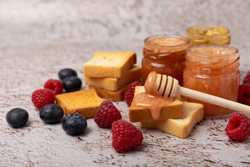 Toasted bread toast with jam. A jar of raspberry jam. Delicious toast with sweet jam served for breakfast on the table. Delicious toasts on a textured background. Space for text. Place for copying.