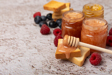 Toasted bread toast with jam. A jar of raspberry jam. Delicious toast with sweet jam served for breakfast on the table. Delicious toasts on a textured background. Space for text. Place for copying.