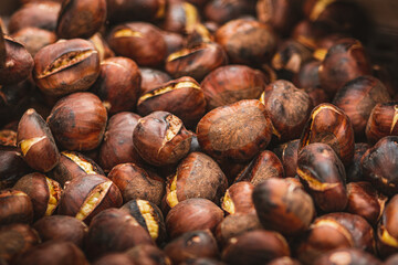 Roasting chestnuts in a bowl or grill on an open fire in a street food market, close up
