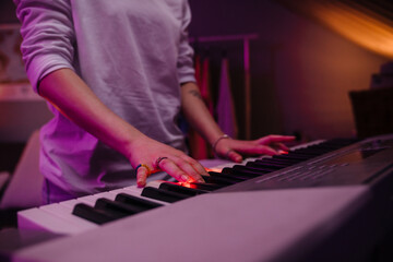 Young woman wearing longsleeve playing synthesizer at home