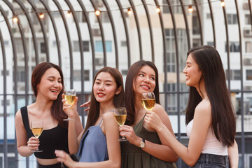 happy asian woman teenagers cheering and toast with white sparkling wine glass to celebrating at dinner party in summertime. celebration, relationship and freandship concept.