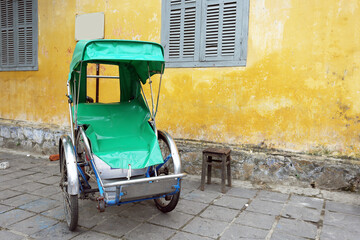Three-wheeler in front of yellow wall in Hoi An, Vietnam