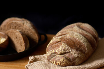 Decorated brown bread on wooden table. Dark composition. Bakery concept.