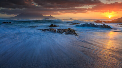 Slow-motion waves during a stormy December Sunset of Table Mountain taken from Bloubergstrand