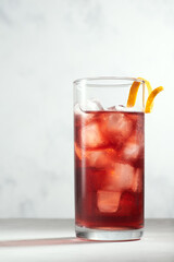 Negroni cocktail in a highball or collins glass with orange peel on a white background. Hero view.
