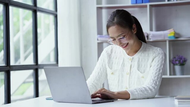 Asian businesswoman working on laptop computer About happy business projects sitting at your desk at home.