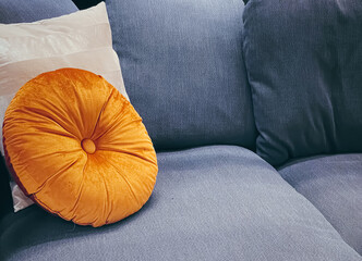 Home decor and interior design, modern blue sofa and orange pillow in living room or office,...