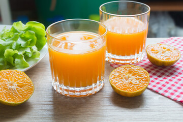 Glass of fresh tangerine juice and orange slice on wood table.