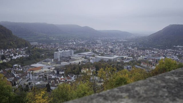 Time lapse shot with view on city of Geislingen from ruins of castle Helfenstein with parts of the wall on a foggy monring in autumn with green and orange trees