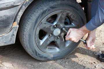 Fototapeta na wymiar A man unscrews a flat car tire outdoors. Wheel replacement