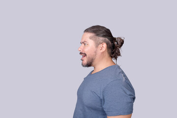 A man in his 30s in disbelief while looking at something. Reacting negatively. Side view on a gray background.