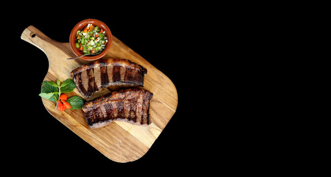 Picanha. Brazilian steak grilled in barbecue. Two slices of Picanha with green sauce, farofa, knife, vinagrete. Brazilian food