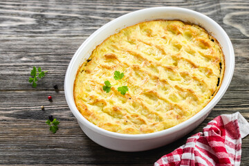 Turkey potato casserole in baking dish on wooden background. Top view, copy space, flat lay.