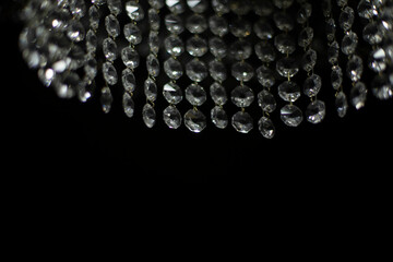 Crystal chandelier on black background. Interior details. Light in room. Light source. Glass sticks.