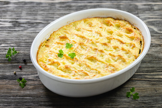 Potato gratin in baking dish on wooden background. Top view, copy space, flat lay.