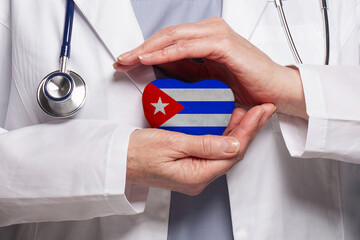 Cuban doctor holding heart with flag of Cuba background. Healthcare, charity, insurance and...